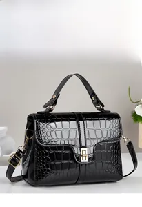 Détail du sac à main noir texture crocodile avec fermoir doré et fini brillant