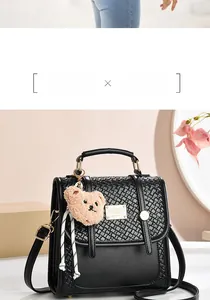 Detail of black woven leather handbag with bear charm and adjustable shoulder strap