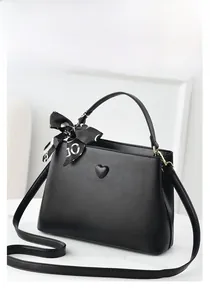 Detail of black textured PU leather bucket bag with heart metal accessory and silk scarf