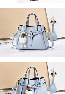 Detail of light blue lychee texture leather handbag with white plush ball charm accessory