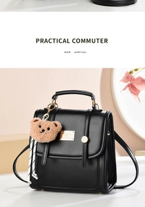 Detail of black faux leather handbag featuring a gold logo and a plush bear charm