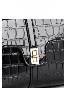 Détail du sac en cuir brillant noir texture crocodile avec fermoir tournant en métal doré