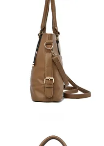 Detail view of caramel brown pebbled leather bag with golden metal buckles and side straps