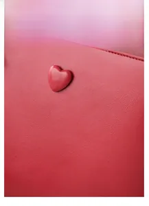Macro shot of red heart ornament on crocodile texture bridal handbag leather
