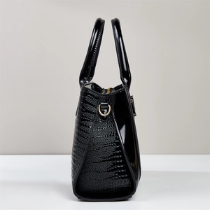 Close-up of black crocodile pattern leather bag with shiny panels and gold ring detail