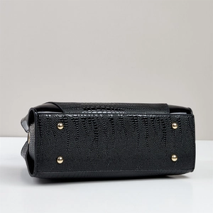 Detailed view of the black crocodile-embossed leather bag base with golden metal studs