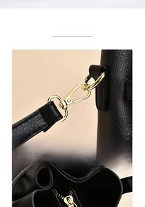 Close-up of shiny gold metal clasps and textured black leather on the crossbody bag