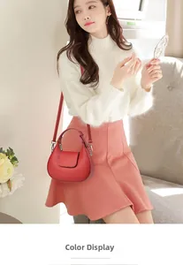 Gros plan d'un sac demi-lune en cuir rouge avec logo embossé et détails métalliques