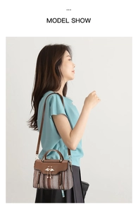 Detail of woven brown handbag with swan clasp, pearl charm and leather top handle