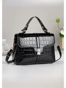 Détail de la texture crocodile noire brillante et de la boucle en métal doré du sac