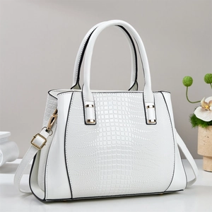 White crocodile embossed tote bag with dual handles and gold hardware in a sleek studio view