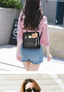 Detail of black woven PU leather backpack with gold clasp and cute bear charm accessory