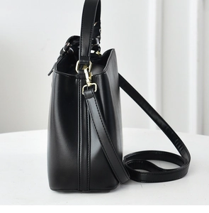 Side view of black leather bucket bag with printed scarf handle and adjustable strap