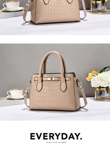 Détail du sac à main beige motif crocodile avec fermoir tournant doré sur le bureau