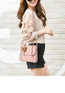 Detail of pink faux leather handbag with top handle, gold hardware and plush bear charm
