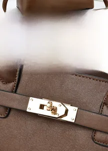 Close-up of golden metal rotating lock on a brown litchi pattern leather handbag