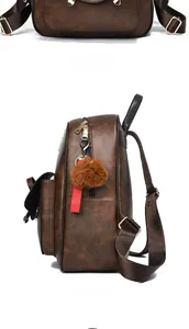 Détails d'un sac à dos en similicuir marron avec zips dorés et pendentif en peluche