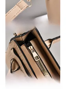 Détail de la boucle en D dorée et de la fermeture éclair sur sac en cuir beige gaufré