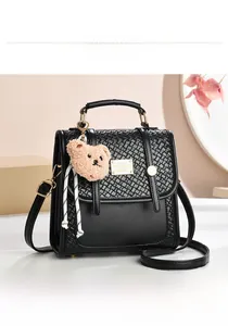 Front view of black PU handbag with woven texture, metal plate, and plush bear charm
