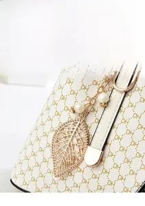 Vue détaillée du cuir crème avec imprimé DH et pendentif feuille dorée élégant