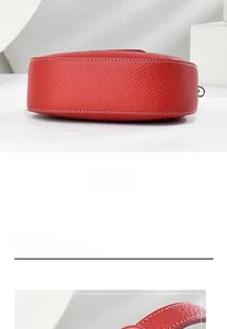 Détail du bas du sac à main en cuir rouge avec coutures blanches et texture lychee