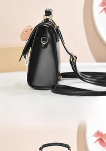 Detail view of black faux leather backpack side profile with golden hardware and bear charm