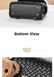 Detail view of black textured leather bag bottom with gold studs and bear charm