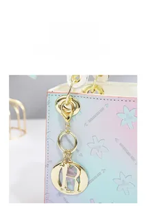 Close-up of golden R-letter pendant on pink and blue gradient handbag surface