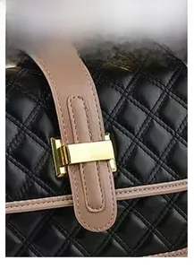 Macro shot of black quilted faux leather crossbody bag with golden buckle and chain detail