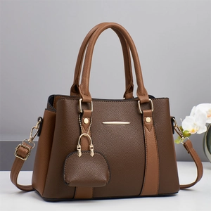 Close-up of textured leather stitching and gold hardware on a two-tone tote bag