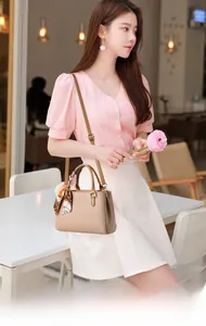 Dettaglio borsa beige in pelle a grana con foulard arancione decorativo sul manico