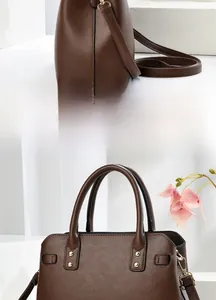 Detail view of dark chocolate leather handbag showing gold studs and adjustable shoulder strap