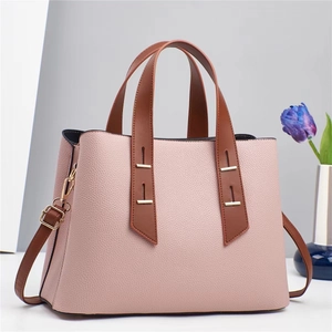Vue détaillée du cuir rose à grain litchi et de la poignée marron sur ce sac à main