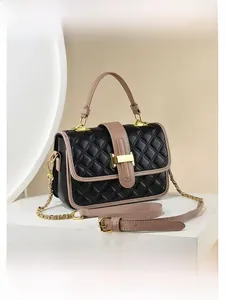 Close-up of black quilted leather crossbody bag with dusty pink handles and gold clasp