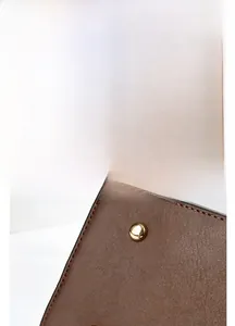 Detail of brown leather bag base with golden metal studs and precise stitching