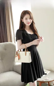Dettaglio di elegante borsa in ecopelle color crema con foulard e manico marrone