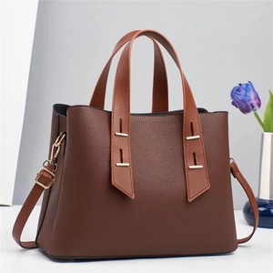 Détail du sac à main en cuir marron avec garniture dorée et bandoulière amovible