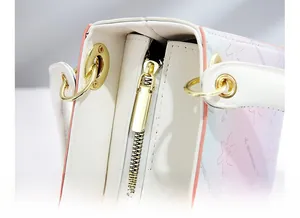 Detail of gold metal zipper and gradient blue-pink leather with leaf pattern on handbag