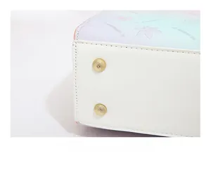 Detail of the gold metal feet on a white leather base of a gradient ladies handbag
