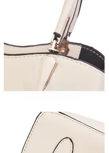 Detail of cream white leather handbag featuring reinforced handle and gold metal hardware