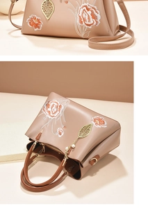 Détails de broderie florale sur sac à main beige avec pendentif feuille dorée élégant