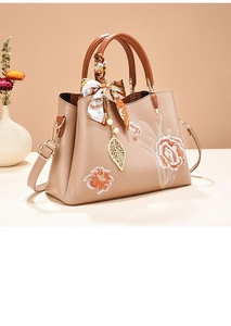 Détail du sac à main kaki avec broderies florales orange et poignées décorées d'un foulard