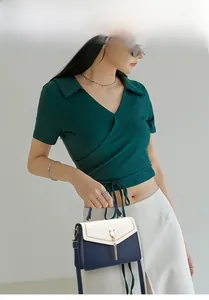 Detail of navy and cream color-block handbag with cat-shaped metal buckle and tassel