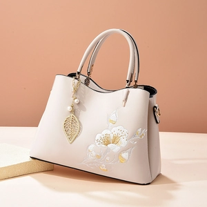 Elegant off-white handbag with gold floral embroidery and pearl leaf charm detail