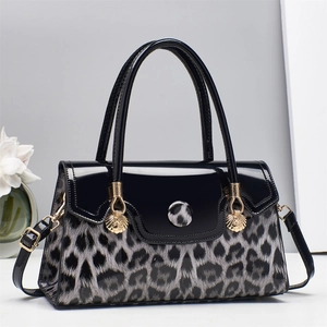 Sac à main chic en cuir verni noir et léopard avec détails dorés en forme de coquillage