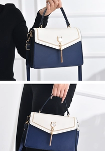 Detailed view of two-tone navy and cream handbag with cat-shaped pearl tassel charm