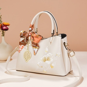 Elegant off-white top-handle bag with floral embroidery, silk scarf, and pearl pendant