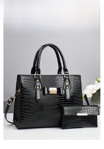 Detail of black crocodile pattern handbag set with golden hardware and floral decor