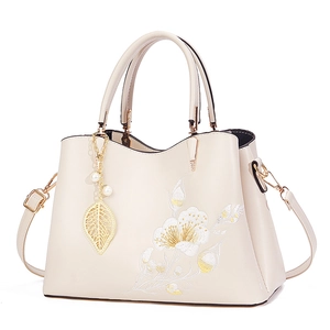 Elegant off-white handbag with floral embroidery and pearl pendant in a 45-degree view