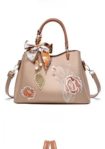 Détails de broderie florale et pendentif perle sur le sac à main en cuir beige